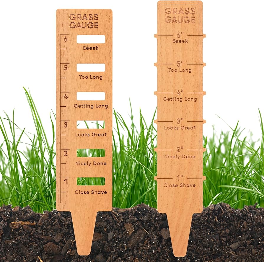 Two wooden grass gauges marked 1–6 inches with labels from Close Shave to Eeeek, set in soil against green turf.